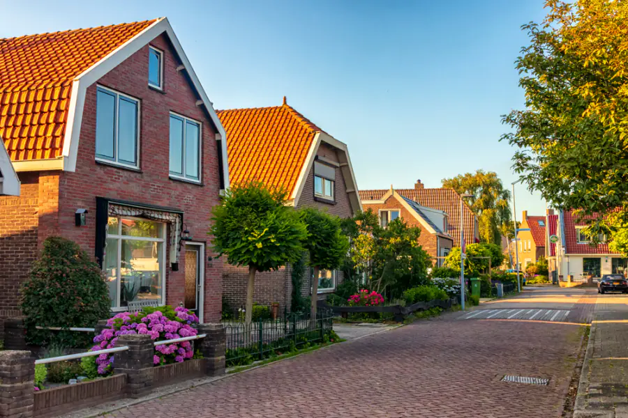 Straat met bakstenen huizen en oranje daken in Akersloot: vergelijk de rijscholen in Akersloot