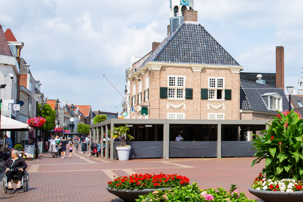 Het plein in het centrum van Almelo met bloembakken: vergelijk de rijscholen in Almelo