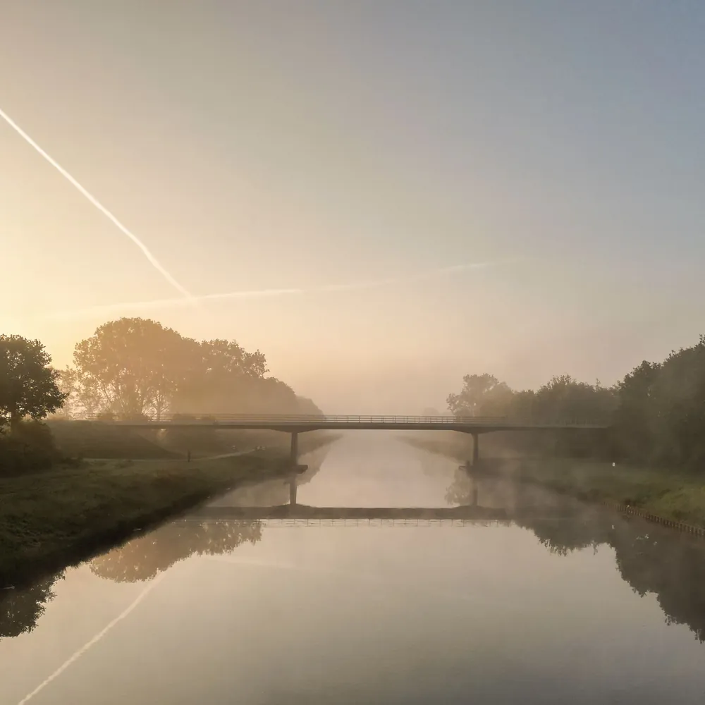 Een brug over het water bij De Wijk in de ochtendmist, waar je de rijscholen in De Wijk kunt vergelijken