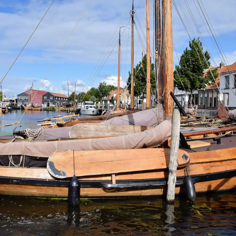 Houten boten in de haven van Elburg: vergelijk de rijscholen in Elburg