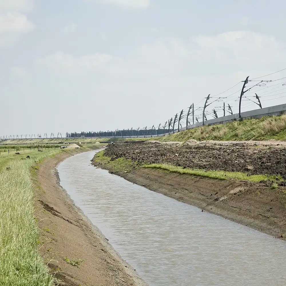 Een sloot langs een spoordijk met bovenleiding bij Meteren: alle rijscholen in Meteren op een rij
